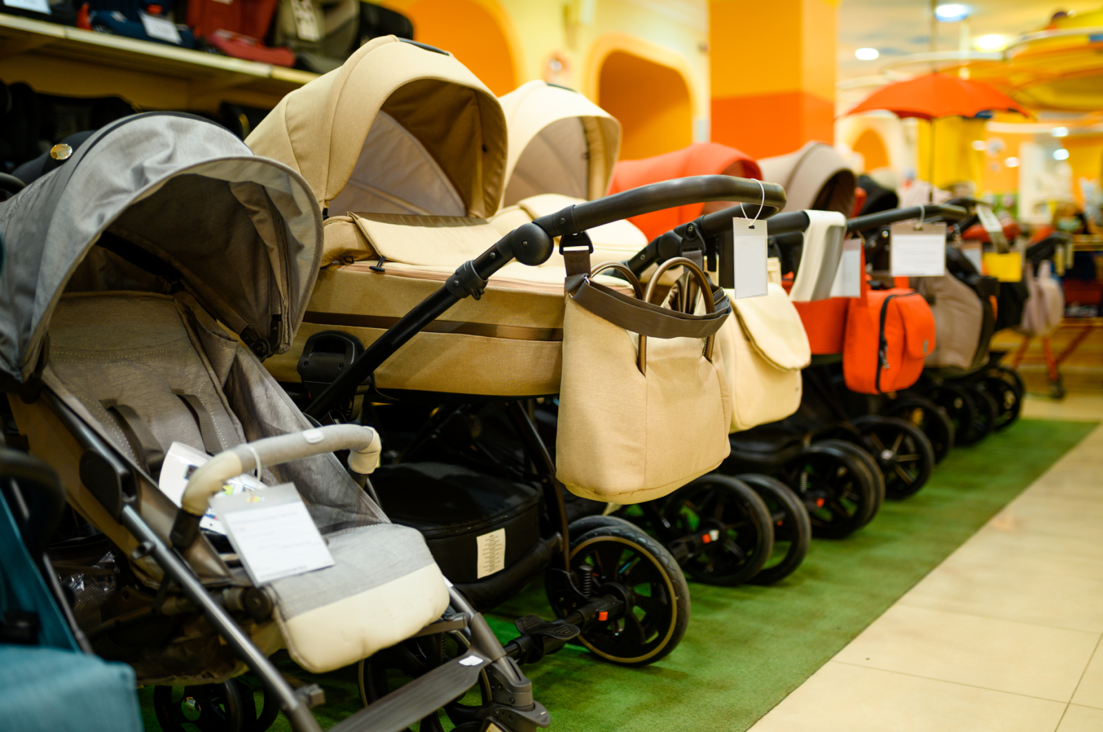 A variety of baby strollers displayed in a store, featuring different models and colors, each equipped with a sturdy handle and spacious storage baskets, catering to diverse preferences and needs in choosing the right baby stroller.